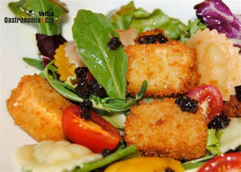 Imagen de una rodaja de queso de cabra rebozado con una textura dorada y crujiente sobre un plato elegante