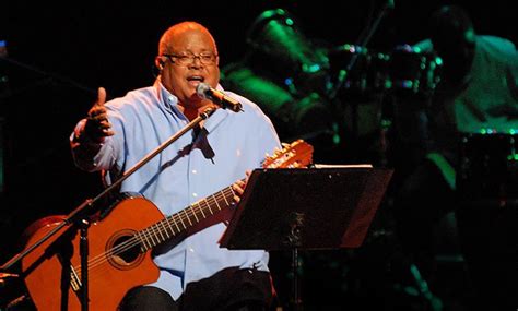 Pablo Milanés en concierto, destacando su guitarra y micrófono