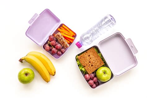 Foto de una lonchera abierta con frutas variadas, yogur y pequeños sándwiches