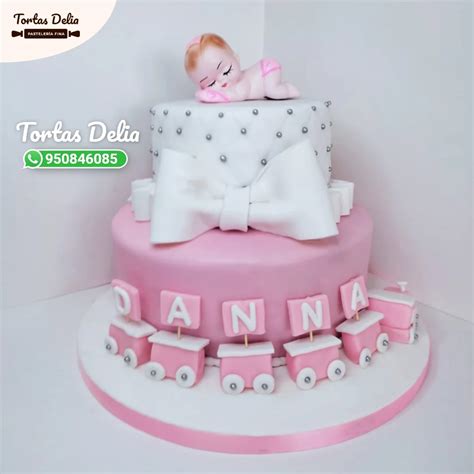 Una torta de baby shower de niña con un diseño de arcoíris, un osito tierno y detalles personalizados con el nombre de la bebé.