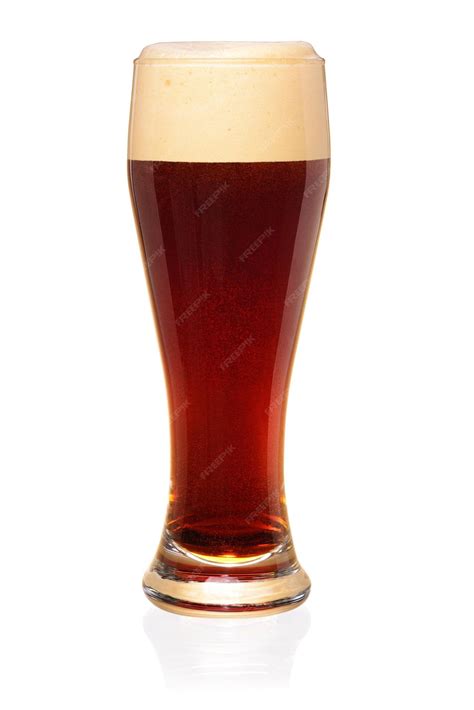 Cerveza oscura en un vaso con espuma y granos de malta tostada.