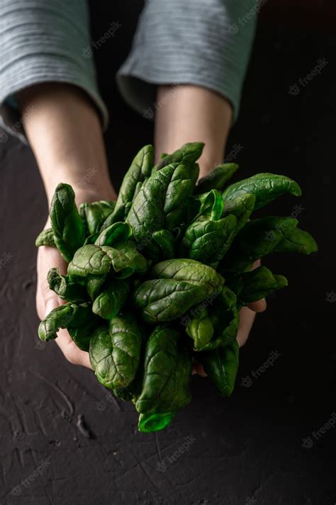 Manos seleccionando espinacas frescas en un mercado