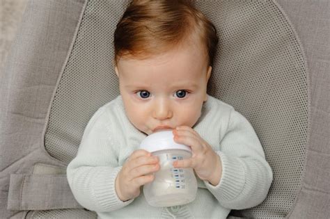 Bebé de un año bebiendo leche de un vaso