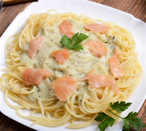 Plato de pasta con salmón desmenuzado, salsa cremosa, alcaparras y perejil