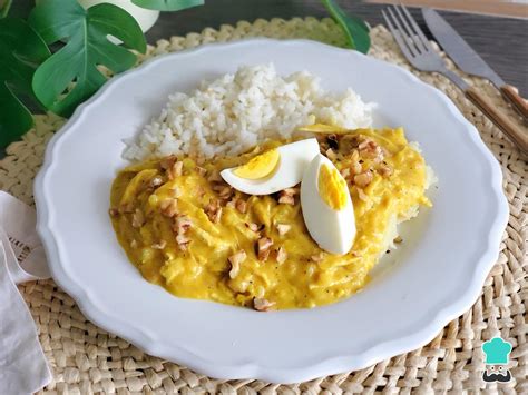 Plato de ají de gallina servido con arroz, rodajas de papa, huevo duro y aceitunas negras