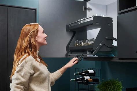 Ilustración de un sistema de elevación iMove Double de Kesseböhmer en un armario de cocina, mostrando los estantes en posición elevada y descendida