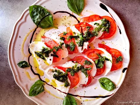 Ensalada Caprese con rodajas de tomate, mozzarella de búfala y hojas de albahaca fresca
