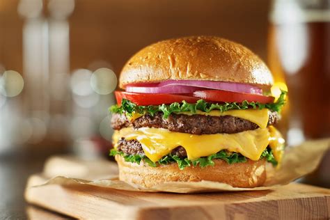 Foto de una hamburguesa doble carne con lechuga, queso y tomate, servida en un plato