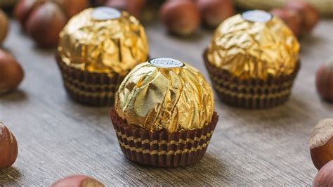Esquema de las capas de Ferrero Rocher: avellana central, relleno de crema de cacao, capa de oblea y cobertura de chocolate con avellanas troceadas.