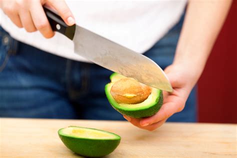Ilustración mostrando cómo cortar un aguacate por la mitad y retirar el hueso.