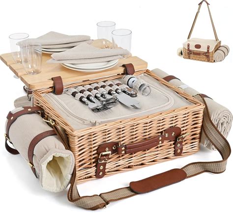 Manta de picnic extendida con cesta, termos y utensilios sobre césped