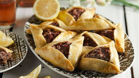Plato de empanadas árabes recién horneadas, decorado con un gajo de limón.