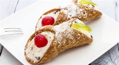 Cannolis sicilianos rellenos de ricotta y decorados con pistachos y fruta confitada