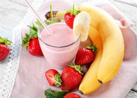 Imagen de un vaso de batido de fresa, manzana y avena listo para consumir, con frutas frescas alrededor