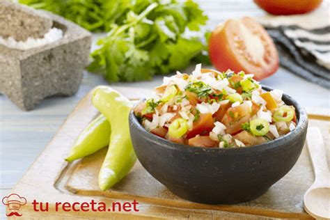Primer plano de pebre de papaya con trozos de la fruta, servido junto a mariscos o pescado