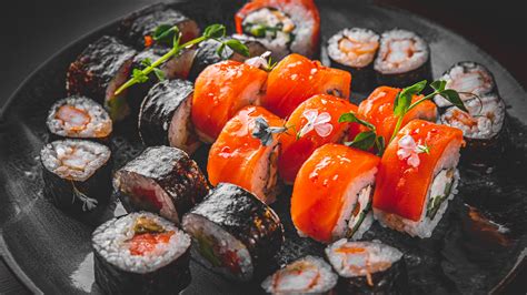 Fotografía profesional de una selección de rolls de sushi variados con presentación estética sobre una mesa de madera.