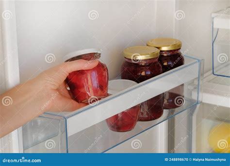 Frascos de vidrio con salsa de frambuesa casera en un refrigerador