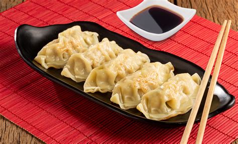 Visualización de Gyozas de Pollo, quizás una porción frita y otra al vapor, mostrando la masa y el relleno