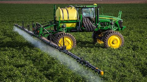 Campo agrícola con plantas sanas y un pulverizador aplicando un producto cúprico.