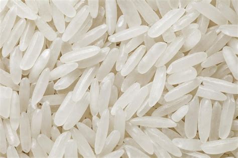 Foto de arroz blanco crudo siendo enjuagado en un colador bajo un grifo