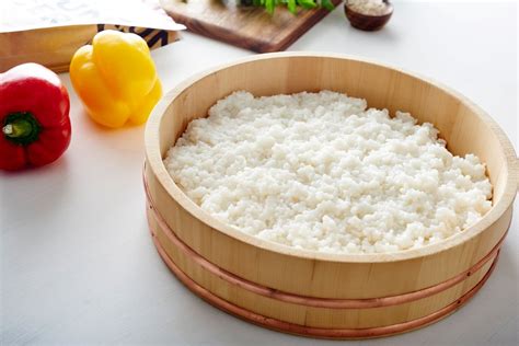 Fotografía de un cuenco de madera (Hangiri) con arroz de sushi siendo aderezado y abanicado.