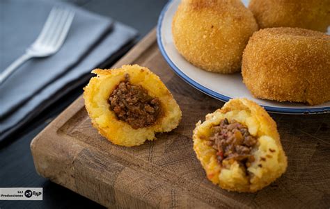 Foto de papas rellenas recién fritas y doradas, acompañadas de ensalada fresca