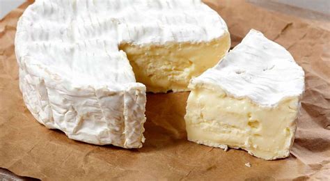 Primer plano de una rueda de queso Brie, mostrando su corteza blanca y la pasta cremosa de color claro.