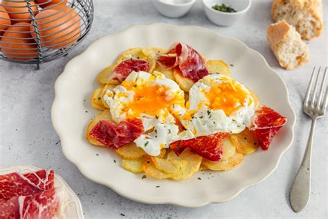 Plato de huevos estrellados bañados en una vibrante salsa roja tradicional, decorados con queso fresco y cilantro.