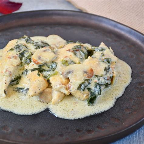Fotografía de un plato de pollo cremoso con espinacas y salsa de parmesano, presentado de forma apetitosa.