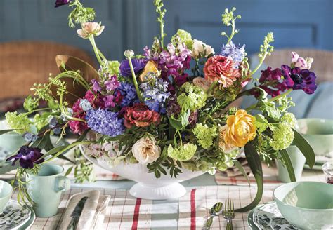 Fotografía de una mesa decorada profesionalmente con bandejas a distintas alturas, flores y etiquetas personalizadas.