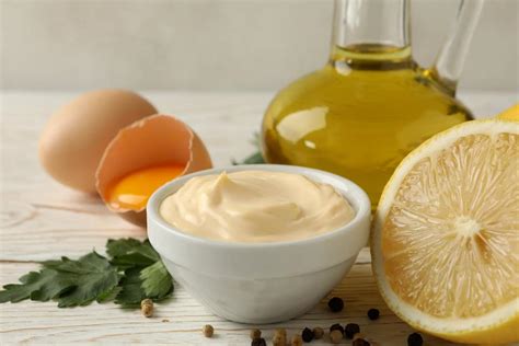 fotografía de mayonesa casera sin huevo en un bol, con ingredientes alrededor como leche, aceite, ajo y limón