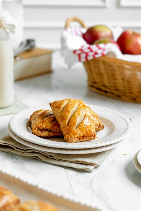 Foto detallada de empanadas de manzana recién horneadas con un acabado dorado y espolvoreadas con azúcar y canela.