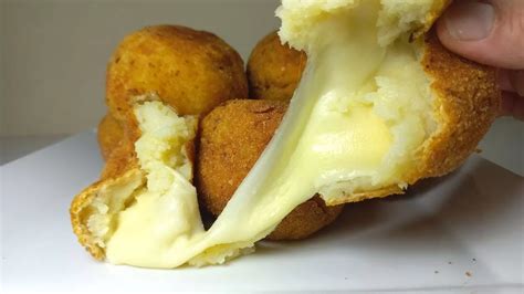 Plato de bombas de papa rellenas de jamón y queso recién horneadas y doradas, con algunas salsas de acompañamiento.