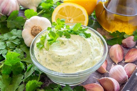 Fotografía profesional de una salsa de mayonesa de ajo cremosa en un cuenco con una ramita de cilantro fresco