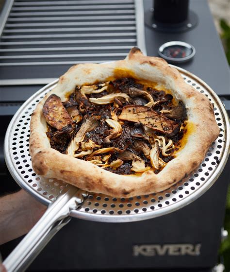 Pizza gourmet de hongos con salsa macha preparada en horno de exterior