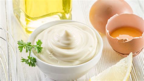 Foto de un tazón de mayonesa junto a ingredientes como huevos, aceite y limón