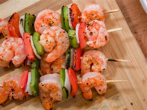Plato de pinchos de camarones con limón y ajo, listos para asar.