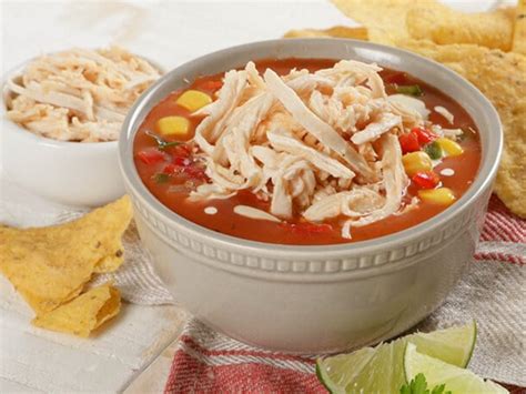 Fotografía de una sopa de tomate mexicana servida en un tazón artesanal con guarniciones de aguacate y totopos.