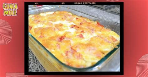 Plato de papas gratinadas con jamón y queso, humeante, con queso derretido y hierbas frescas en una sartén