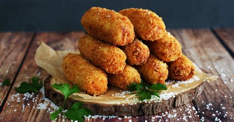 Imagen de una selección de croquetas doradas y crujientes servidas en una fuente rústica