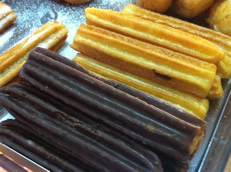 Mesa con churros rellenos, bañados en chocolate y con azúcar