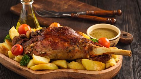 Plato de cordero asado con guarnición de patatas y hierbas
