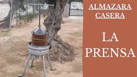 Fotografía de un productor rural utilizando una prensa de aceite tradicional.