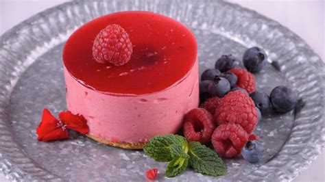 Imagen de copas de vino con capas de mousse de frambuesa y decoradas con frutas frescas y virutas de chocolate.