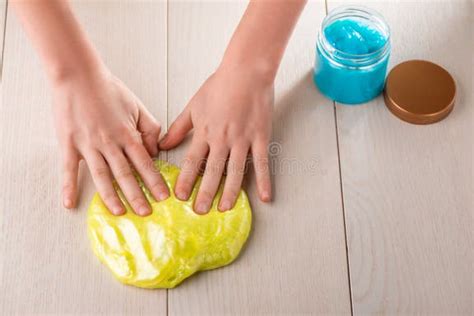 Manos amasando slime azul en un recipiente