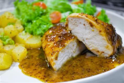 Foto de pollo a la mostaza y miel en sartén, con salsa brillante.