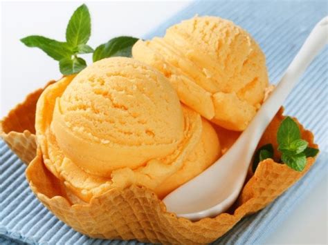 Fotografía profesional de un helado de naranja servido en una masa tulipa artesanal con un hilo de salsa de morrones por encima.