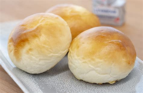 Panecillos de leche y huevo recién horneados en bandeja con una taza de café