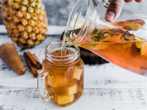 Té de cáscara de piña servido en una taza de cristal con una rodaja de limón y una rama de canela