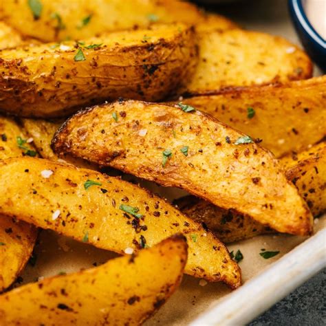 Papas en gajos sazonadas sobre una bandeja de horno
